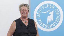 Porträt von Stefanie Boller, die vor dem Logo des Deutschen Tierschutzbundes steht.