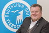 Tierschutzbund-Präsident Thomas Schröder sitzt vor dem Logo des Deutschen Tierschutzbundes