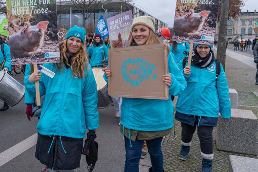 Mitarbeiterinnen des Deutschen Tierschutzbundes demonstrieren auf der Wir haben es satt Demo und halten Protestschilder hoch