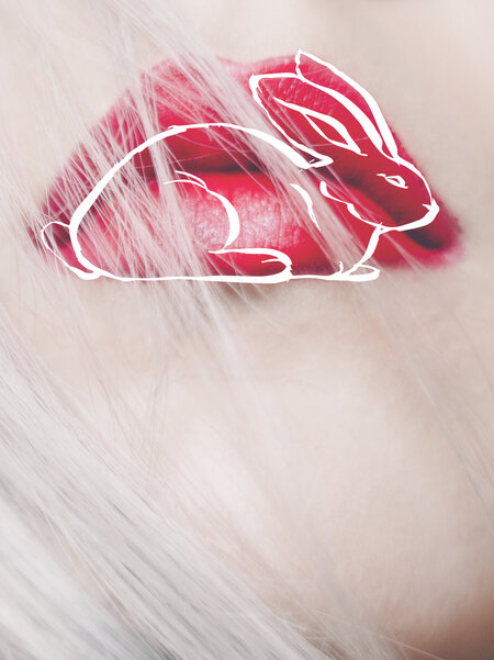 Eine Nahaufnahme zeigt die rot geschminkten Lippen einer hellblonden Frau. Auf ihre Lippen wurde in dünnen, weißen Strichen ein Kaninchen gezeichnet. 
