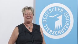 Porträt von Stefanie Boller, die vor dem Logo des Deutschen Tierschutzbundes steht.