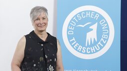 Porträt von Heike Beressem, die vor dem Logo des Deutschen Tierschutzbundes steht.